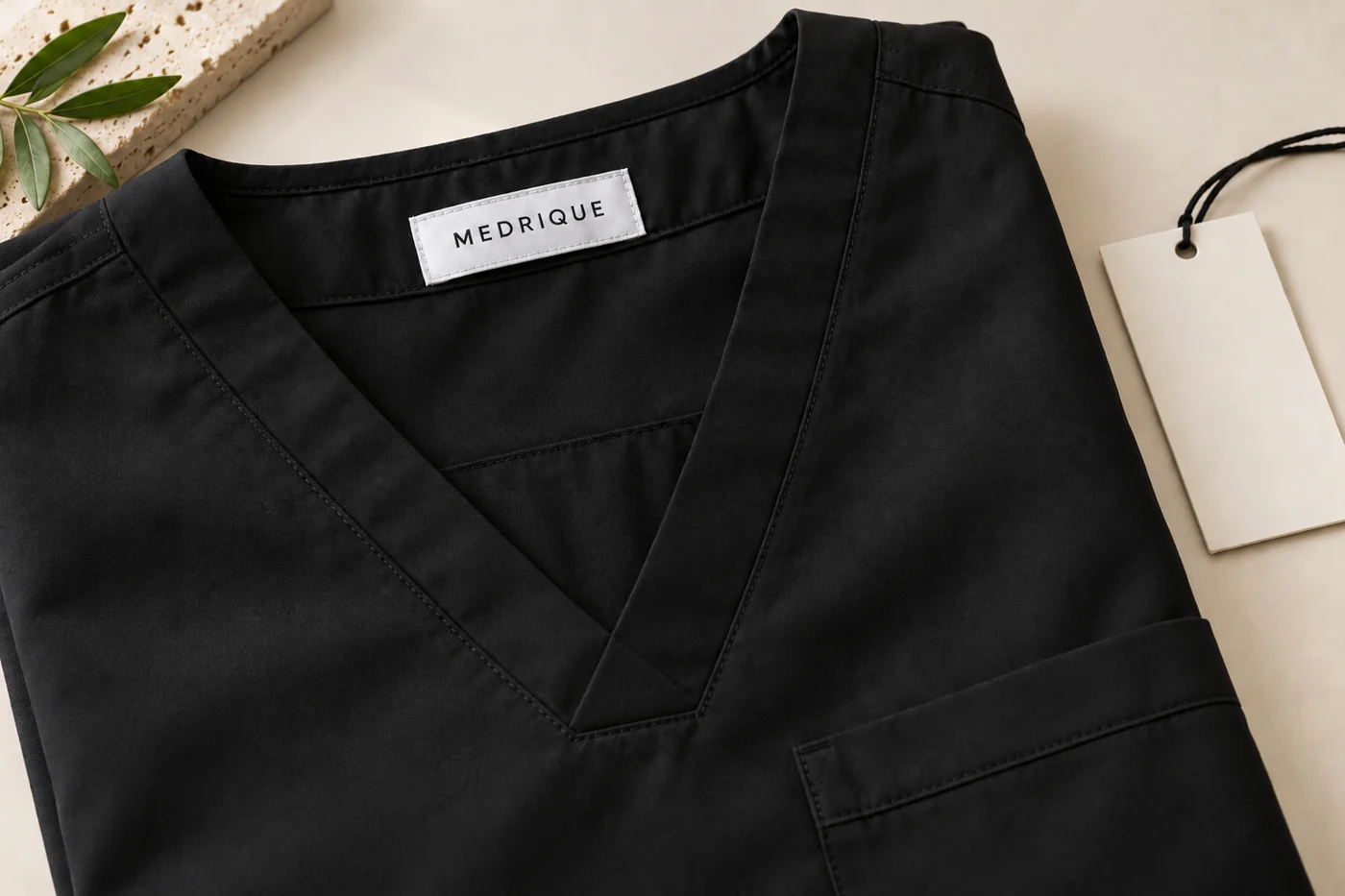 Medrique woven brand label inside a black scrub top